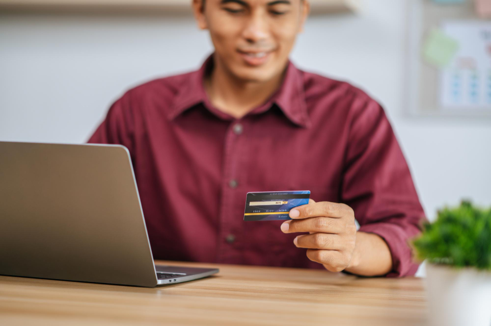 male-employee-uses-credit-card-pay-goods-through-computer